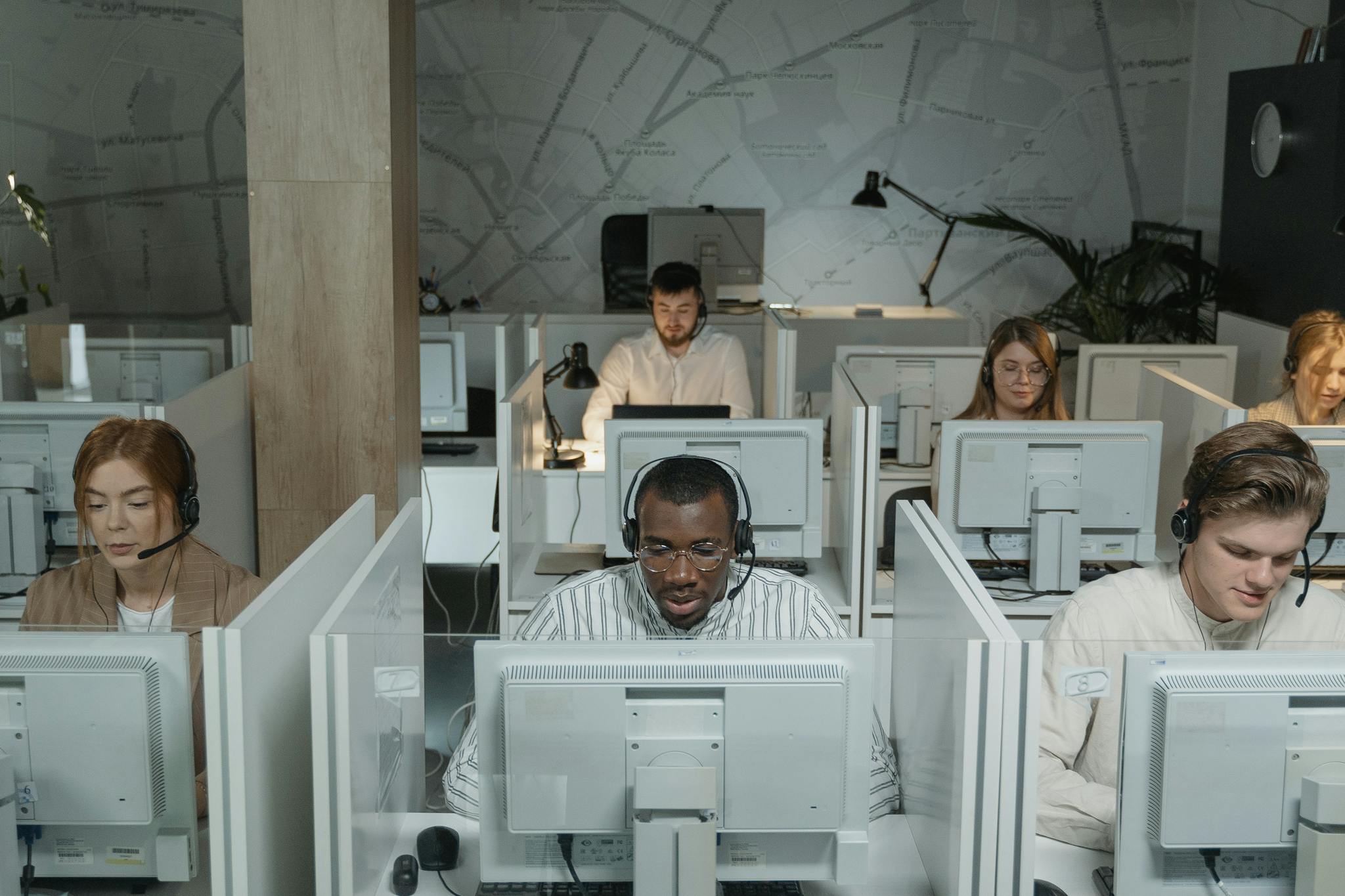 A diverse group of call center agents working in an organized office setting, focused on assisting customers.